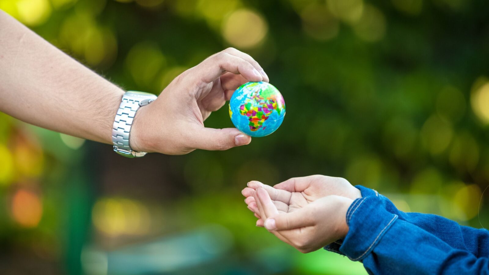 Una mano adulta porge un piccolo globo colorato alla mano di un bambino