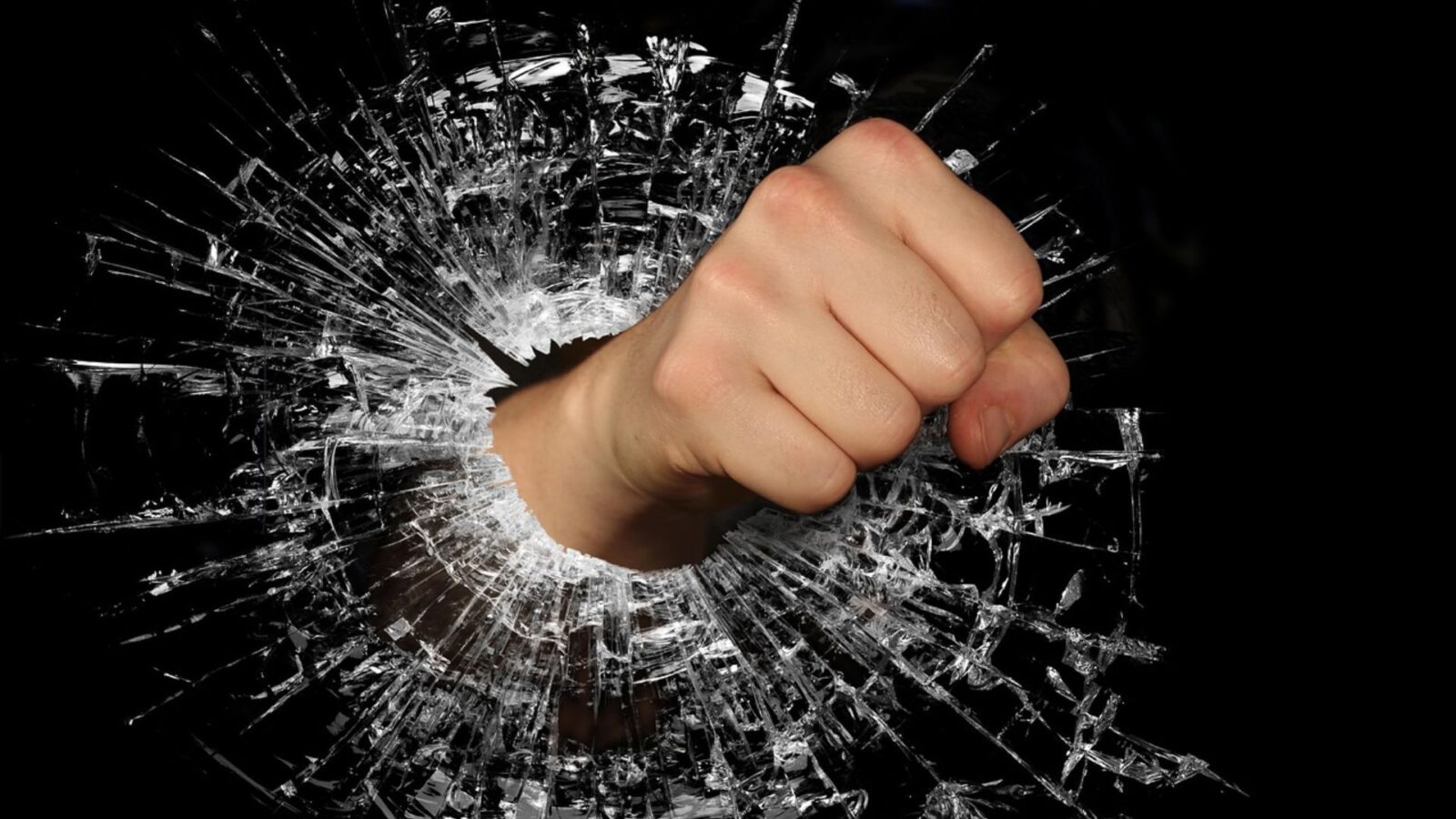 Un pugno infrange una superficie di vetro, immagine simbolica della violenza sul lavoro