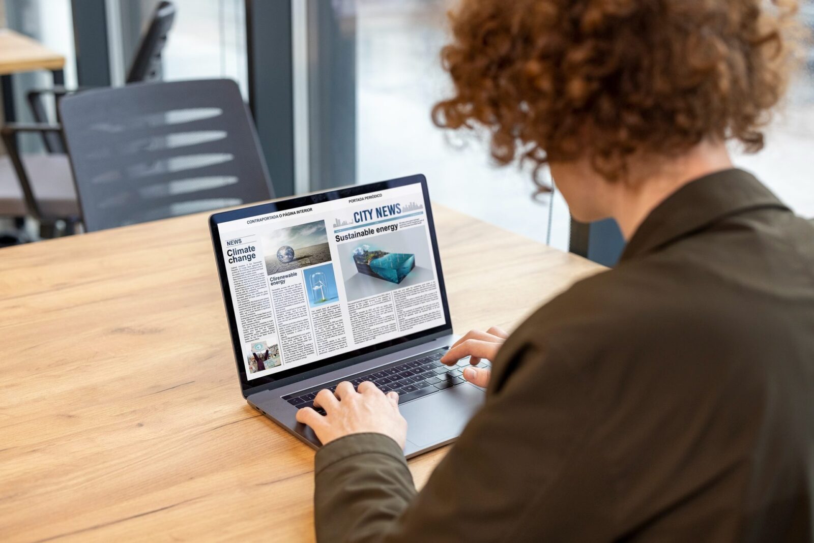Persona di spalle davanti a un portatile con un giornale digitale: "CITY NEWS", "Climate change", "Sustainable energy"