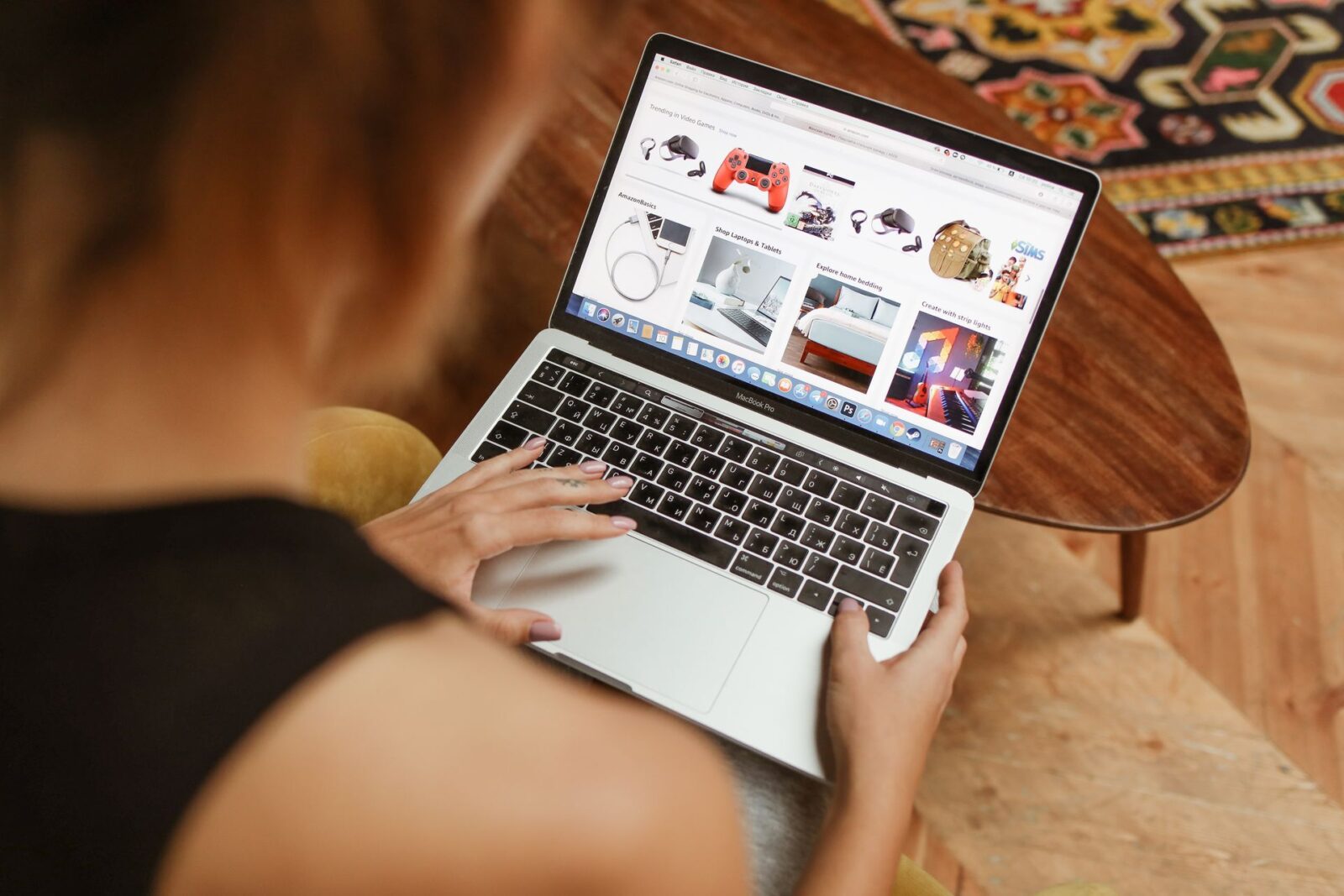 Ripresa da sopra la spalla, una donna naviga su un sito di acquisti online con il portatile appoggiato sulle gambe