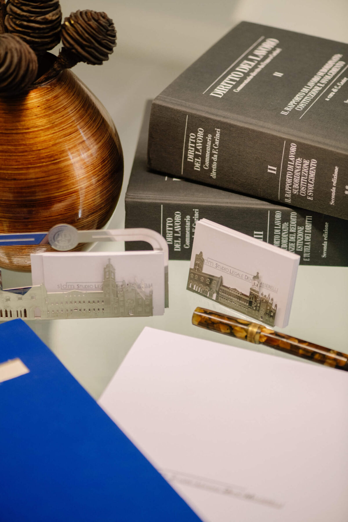 Dettaglio della sala riunioni dello Studio Legale Dehò Masserelli con vaso, libri di diritto del lavoro, documenti e biglietti da visita